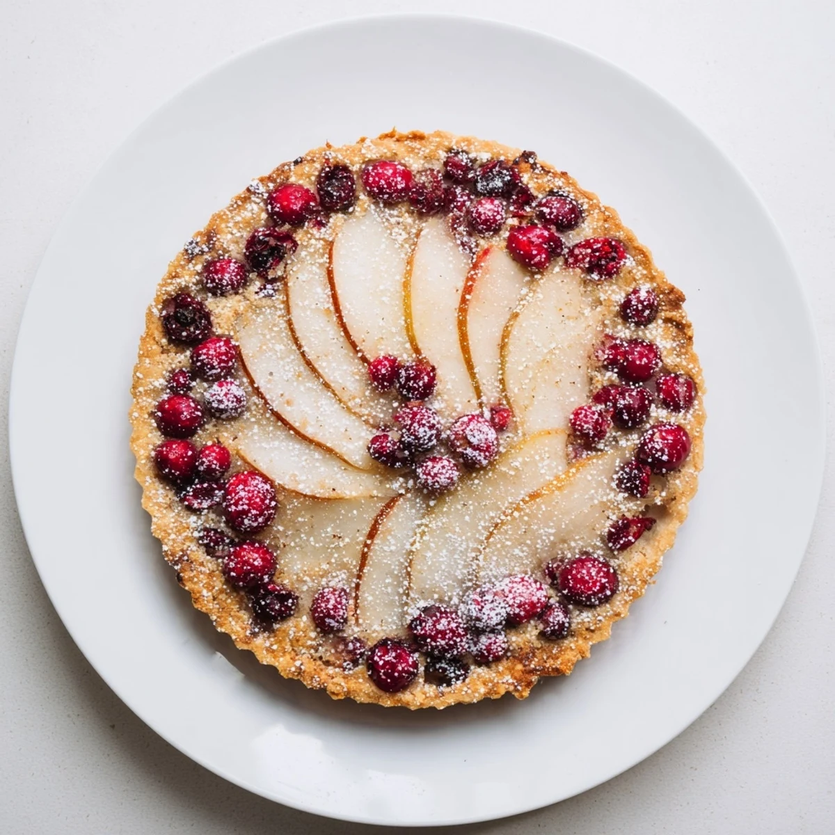 Sliced pears and bright red cranberries nestled in a golden homemade tart crust