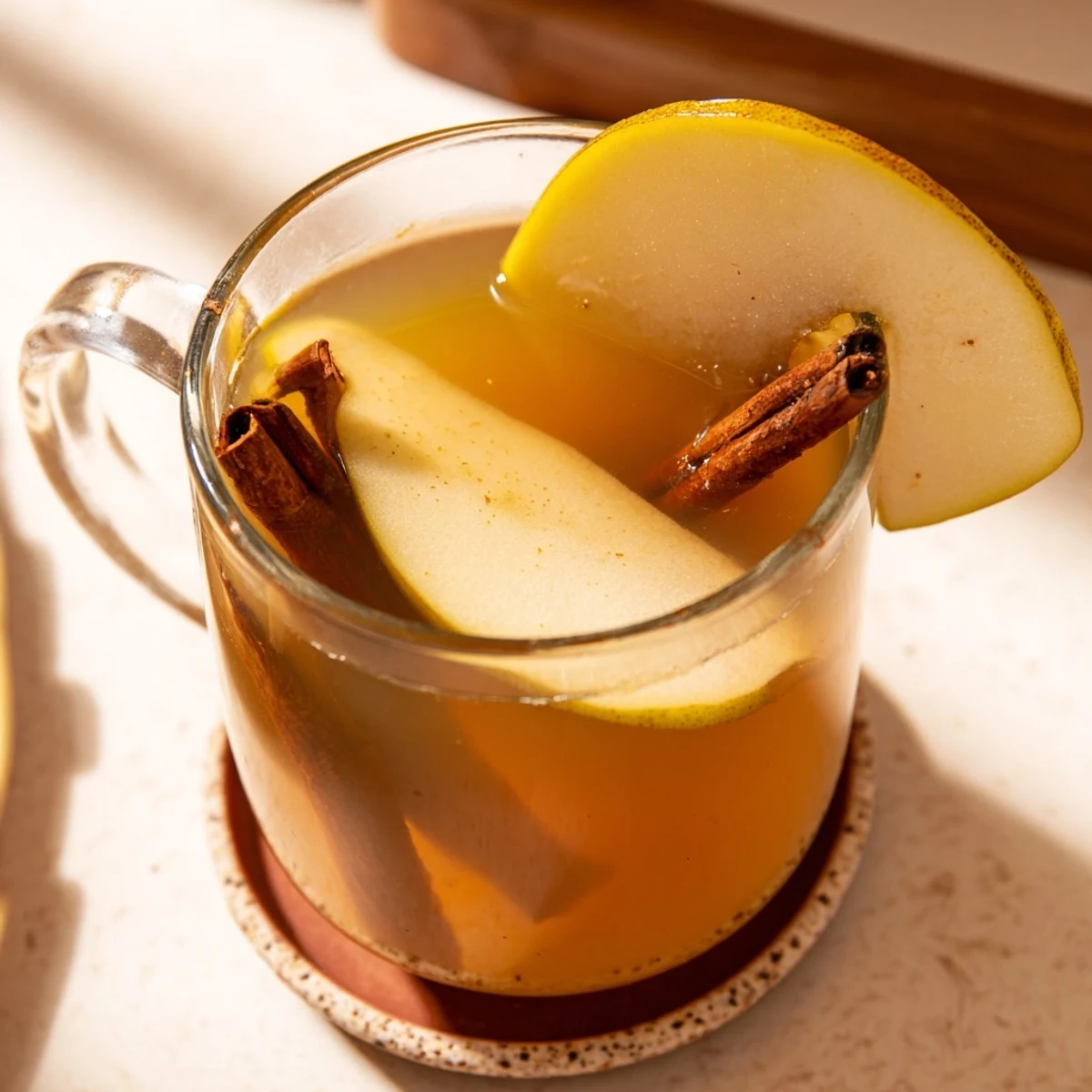 Golden brown pear wedges simmering in spiced apple cider with floating cinnamon sticks and whole cloves