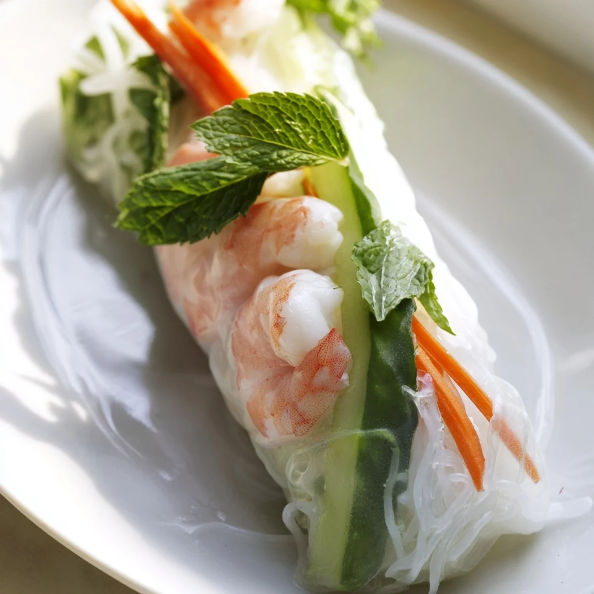 Plate of Vietnamese fresh spring rolls with peanut sauce featuring vibrant carrot, cucumber, and herbs wrapped in delicate rice paper