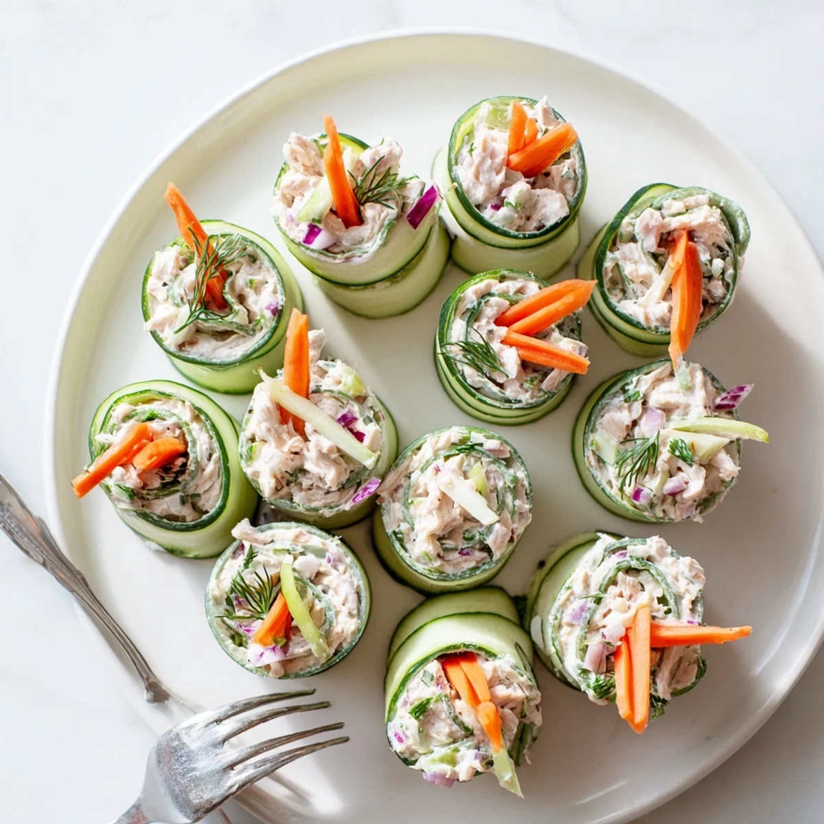Fresh chicken salad rolled inside crisp cucumber ribbons garnished with dill for a light gluten-free appetizer