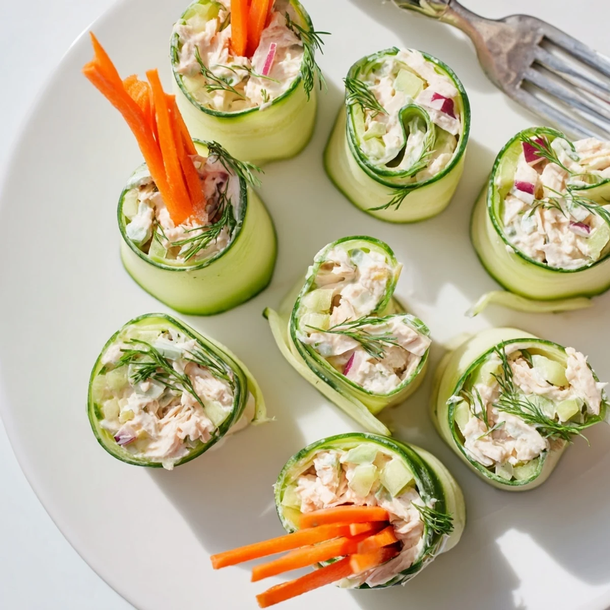 Close up of chicken salad cucumber roll ups bite sized appetizers with visible celery and red onion pieces