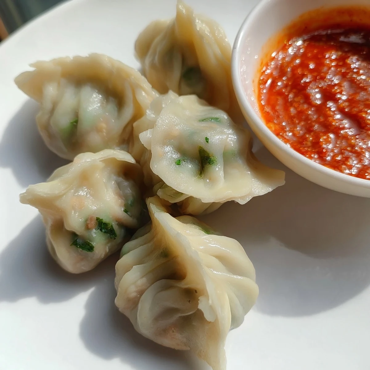 Steaming hot Nepali momo dumplings arranged on a bamboo steamer with pleated edges