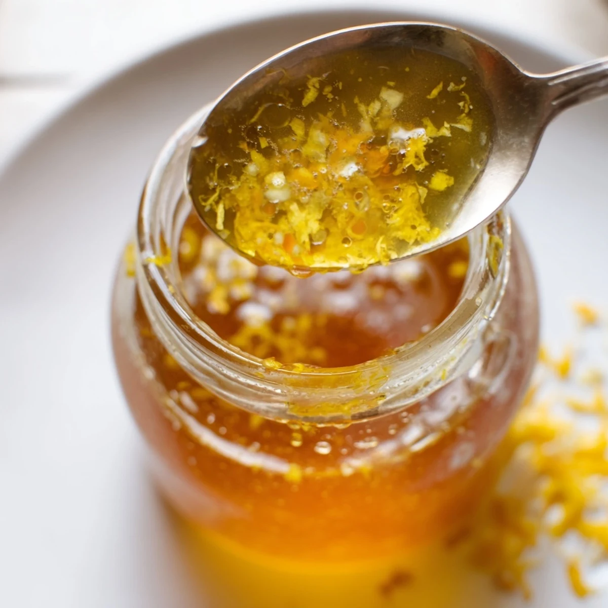 Golden citrus vinaigrette cascading over crisp mixed greens in a rustic wooden serving bowl