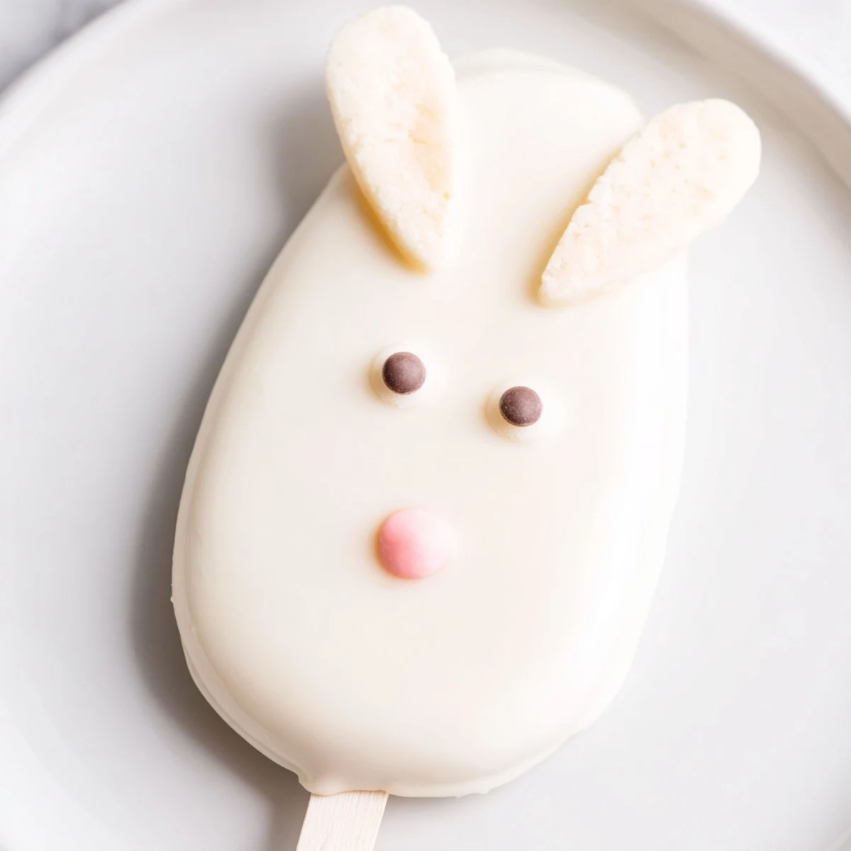 Adorable white chocolate bunny cakesicles with candy eyes and pink ears on sticks