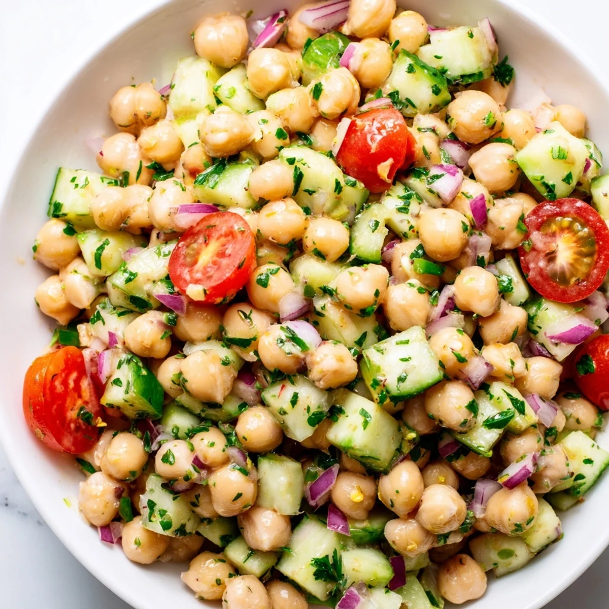 Creamy chickpea cucumber salad topped with fresh herbs in a bright lemon dressing