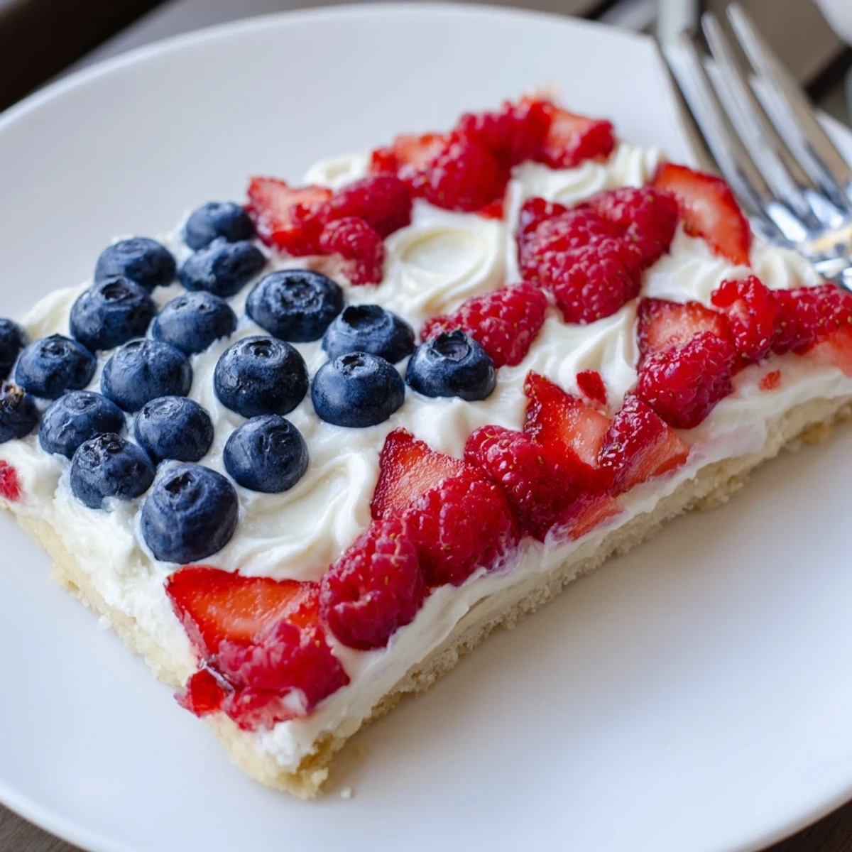 Chilled Sugar Cookie Flag Fruit Pizza sliced on parchment, juicy strawberry stripes