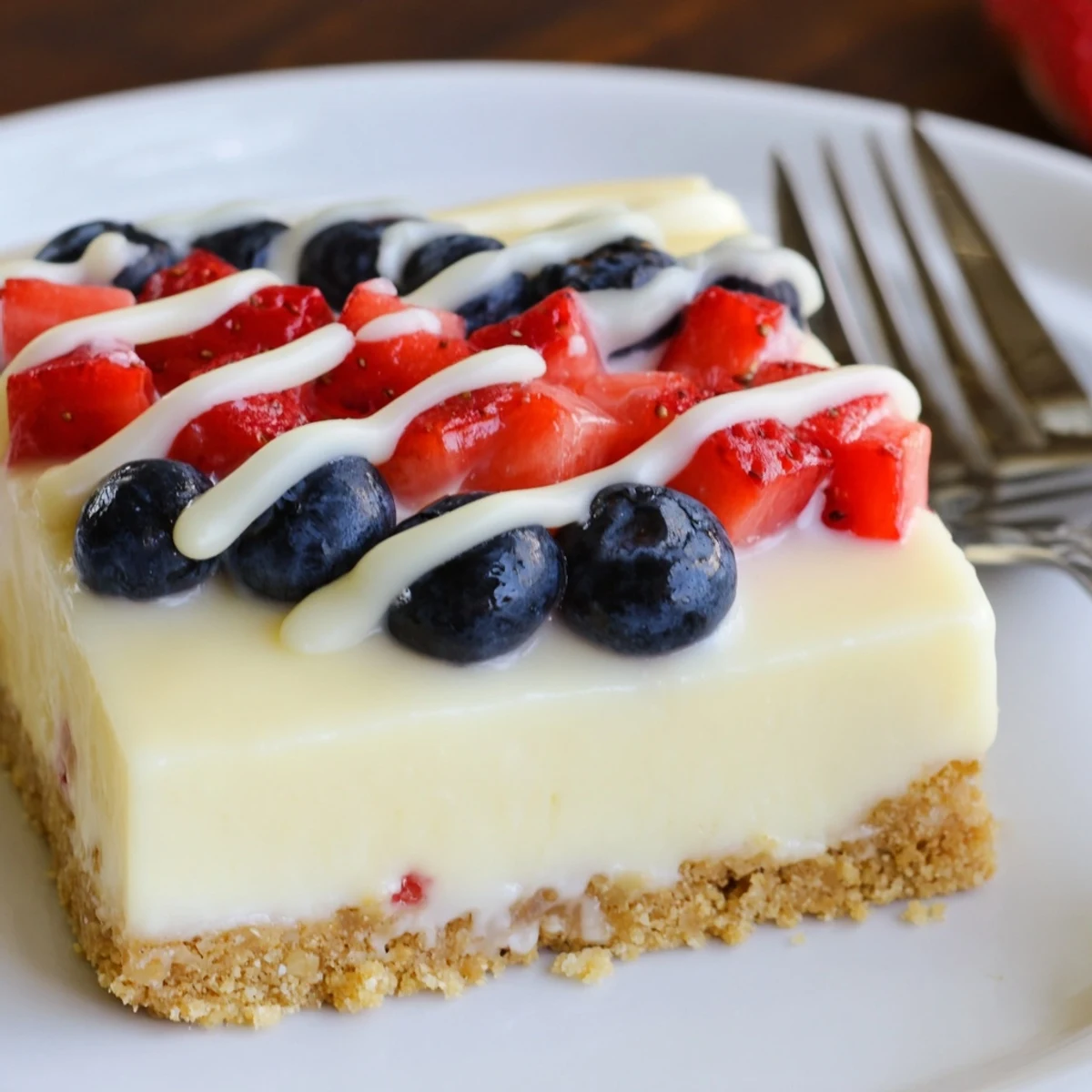 Close-up of Patriotic Cheesecake Bars with buttery graham crust and glossy berries