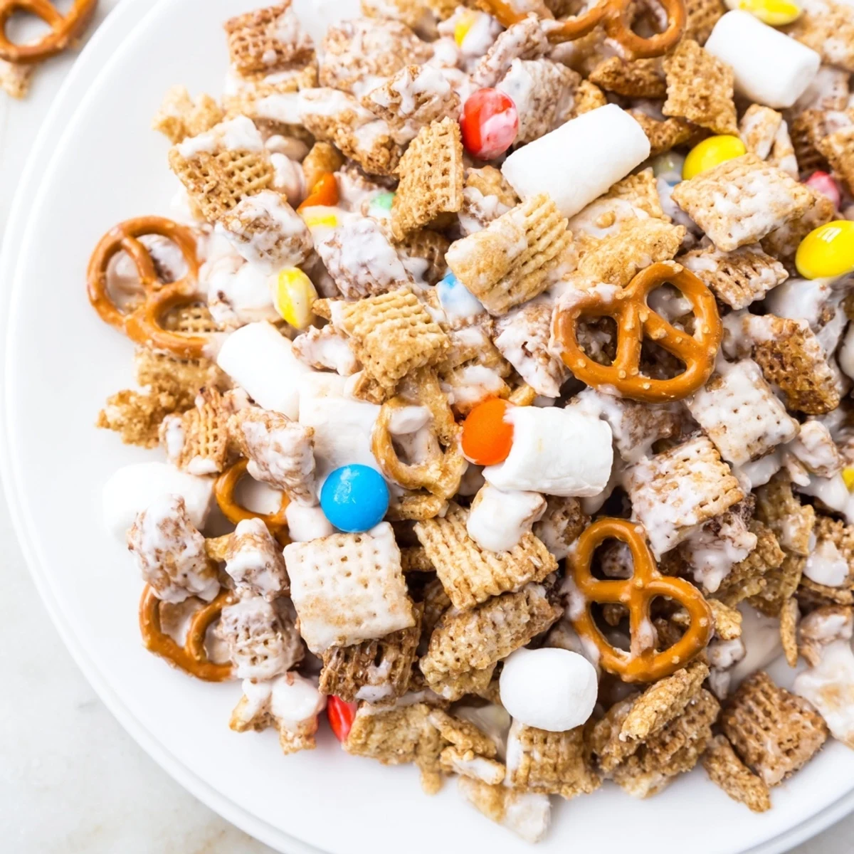 Festive White Trash Snack Mix drizzled with melted white chocolate, ready to share