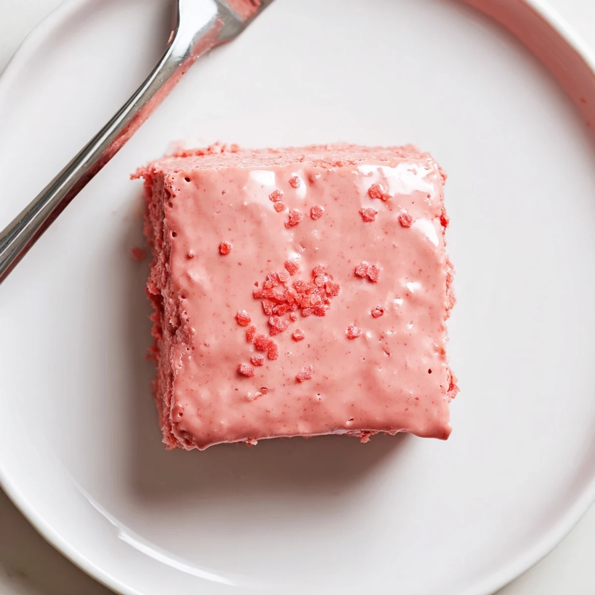 Fudgy Strawberry Brownies glazed with pink icing, sliced on parchment, steaming.