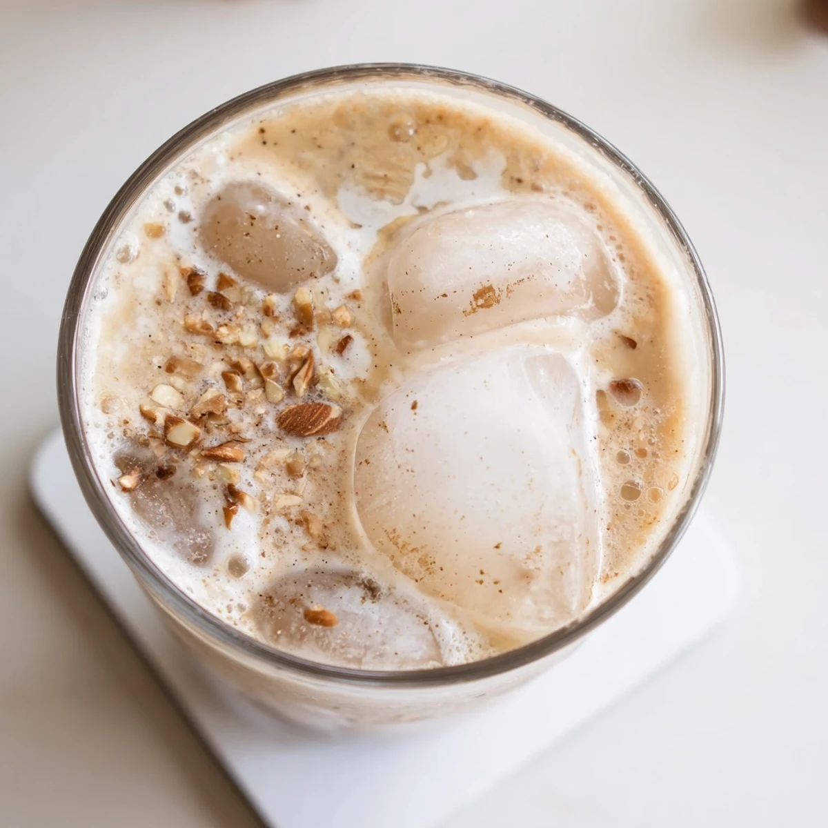 Chilled glass of refreshing summer roasted almond milk drink topped with fluffy whipped cream