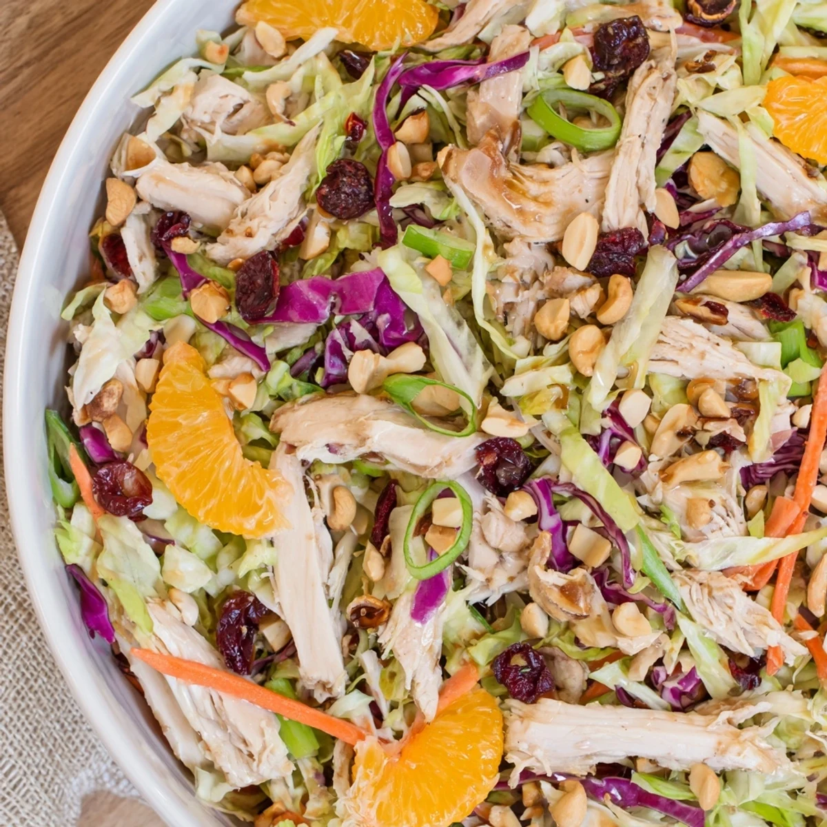 Fresh Asian chicken cranberry salad in white bowl with colorful cabbage crunch and sesame dressing