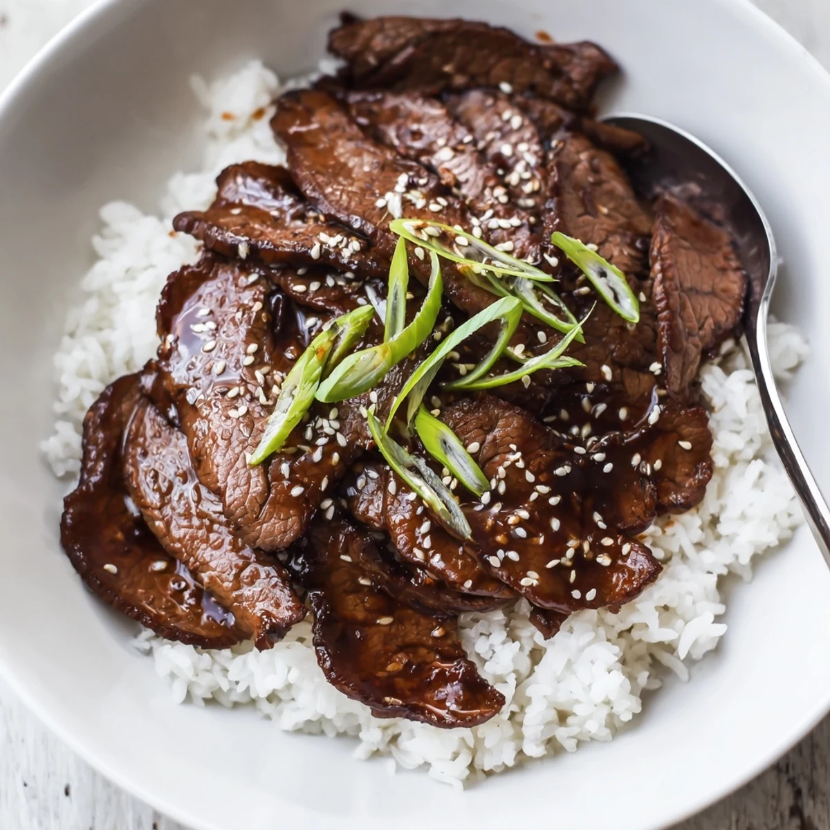 Korean Beef sizzling in a skillet, glossy sauce over steamed rice.