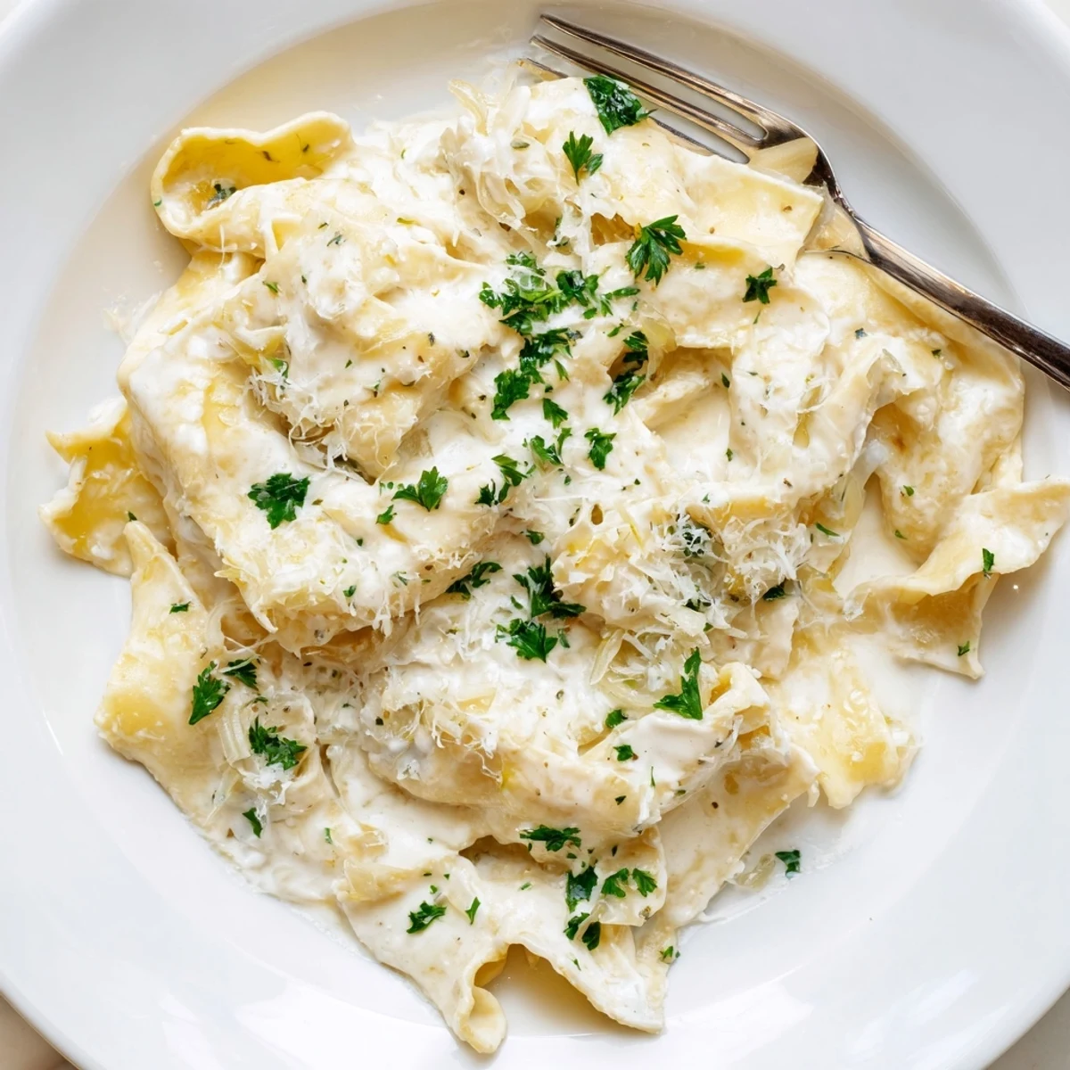 Creamy cafeteria noodles coated in rich Parmesan sauce with fresh parsley garnish on a white plate