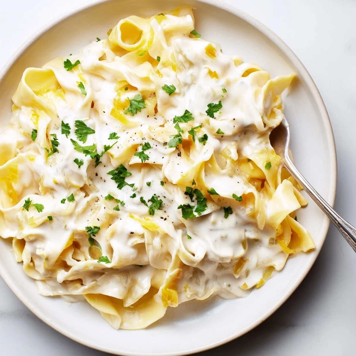 Golden wide egg noodles tossed in velvety white cheese sauce with chopped onion and garlic