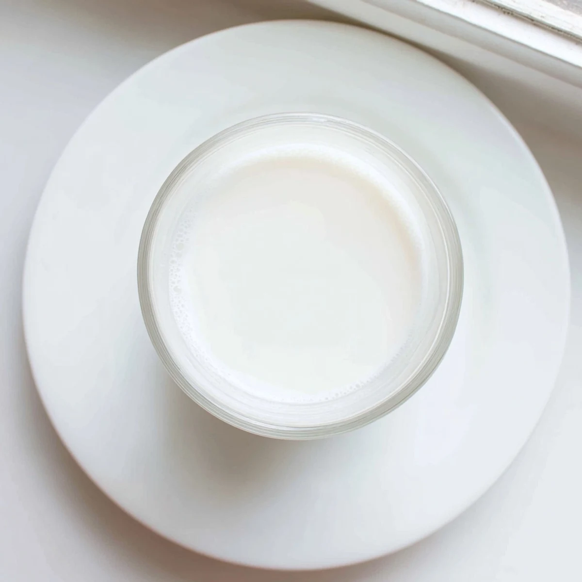 Glass jar filled with fresh homemade almond milk on a wooden kitchen counter