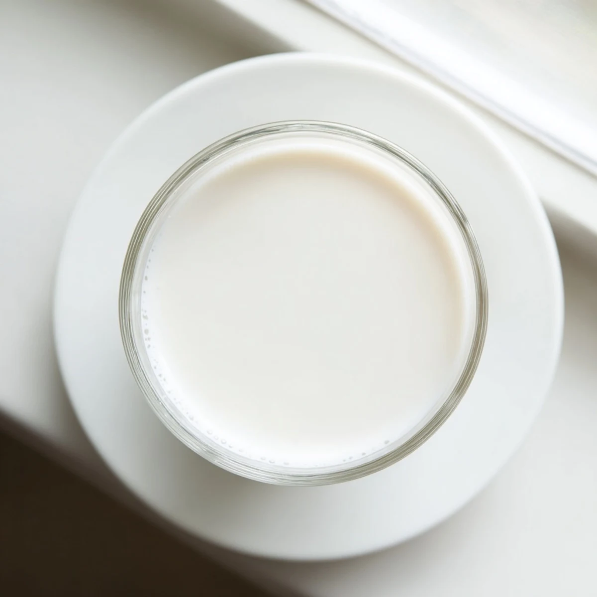 Creamy white almond milk poured from a mason jar into a clear drinking glass