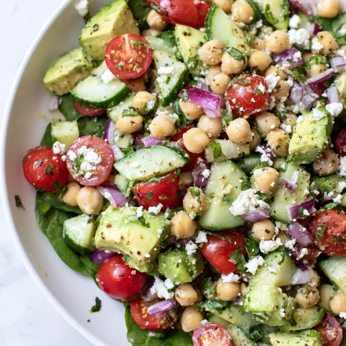 Bright chickpea feta avocado salad topped with crumbled cheese and fresh herbs