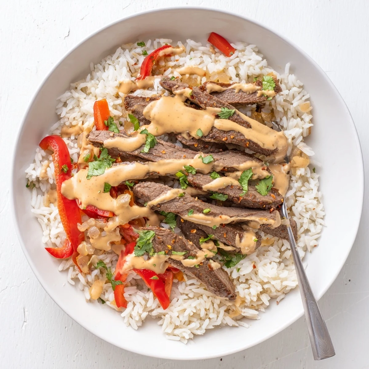 Hearty steak queso rice in a skillet smothered in rich, velvety queso