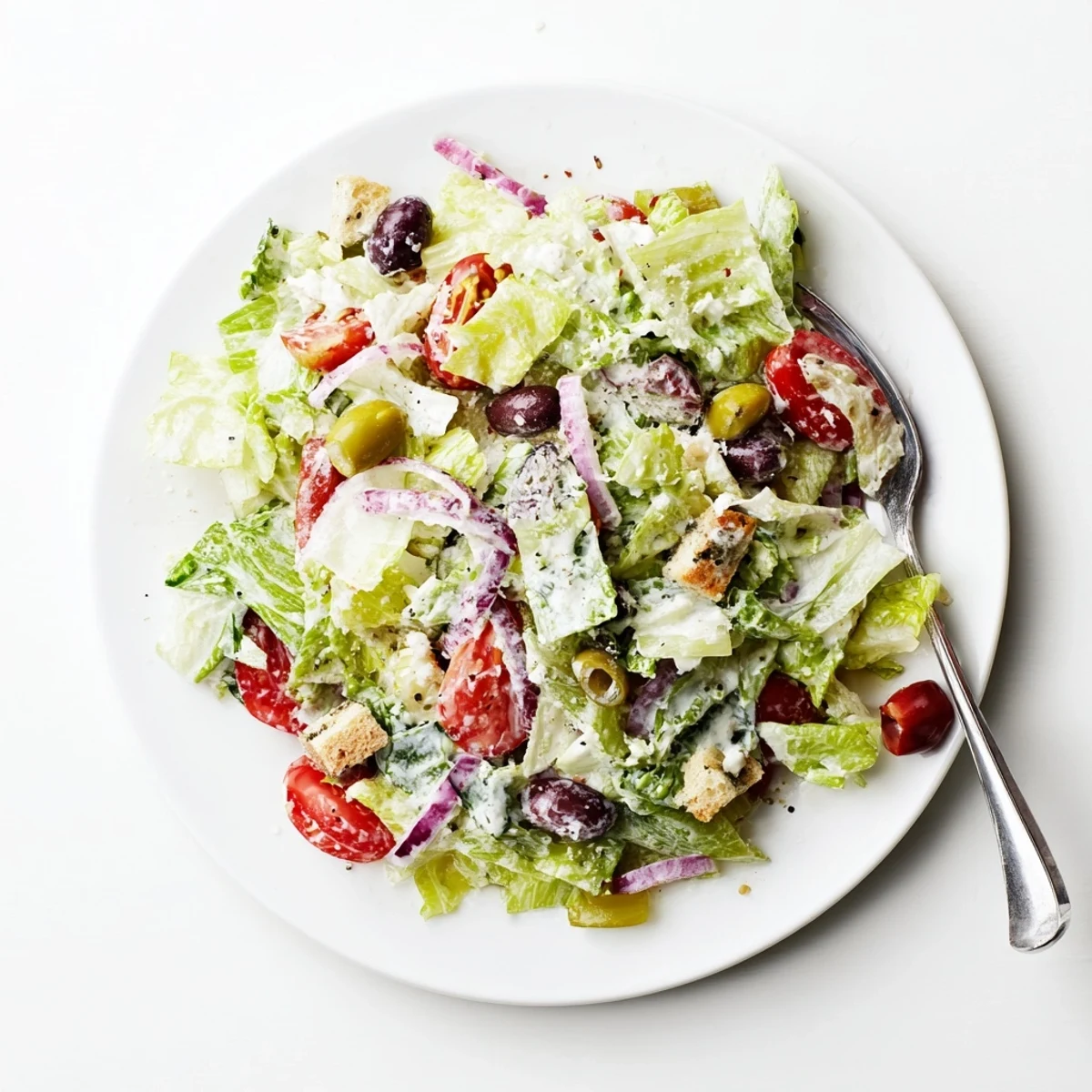 Crisp Olive Garden Salad topped with juicy tomatoes, olives, and creamy dressing