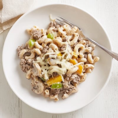 Diced green peppers and sautéed onions mix with creamy pasta in this hearty Easy High Protein Philly Cheesesteak Mac.