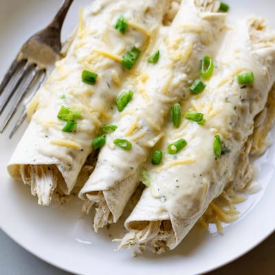 Freshly baked Creamy White Chicken Enchiladas in a casserole, steaming and comforting