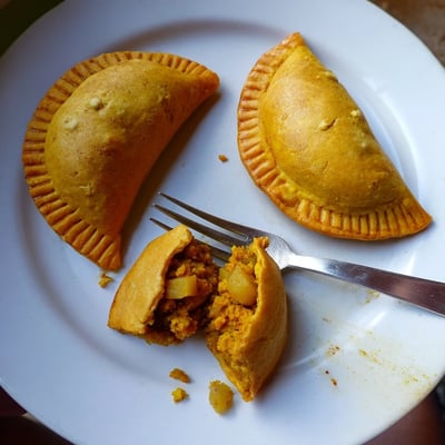 Close-up of Jamaican curry chicken patties with aromatic spiced filling oozing from crisp turmeric-yellow crust